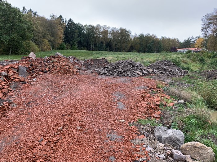 Byggplats med krossad tegel och högar av grus och jord före uppförandet av ett hus.