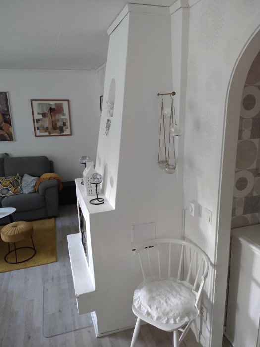 Vit ommålad murstock med dekorativ böjning i ett hem, möblemang synligt.