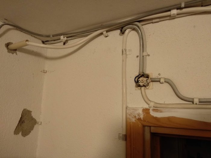 Elledningar och plåtkulor för skyddsledare på en vägg över en dörröppning, oavslutad installation.