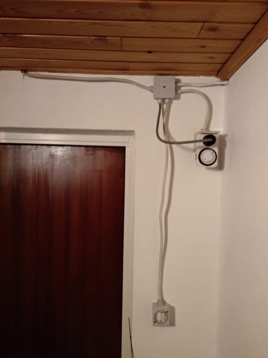 Elektrisk installation med dubbelbrytare och tidur för belysning på vägg ovanför dörr.
