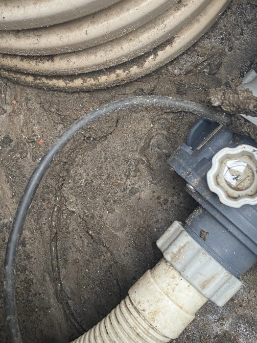 Pumpkablage och del av saltklorinator som ligger under fuktig gyttja.