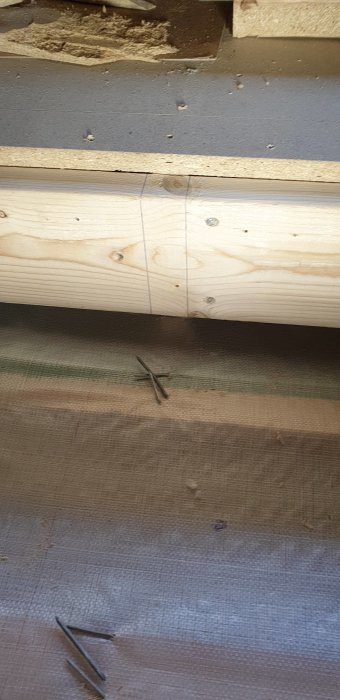 Två träbalkar monterade ihop med skruvar på en byggplats.