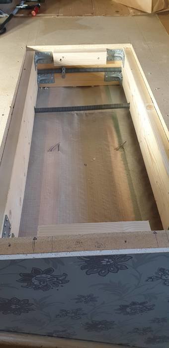 Öppning i ett träbjälklag med monterade stödben och ett synligt rör, klar för installation av rökkanal.