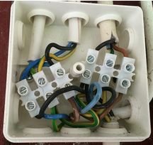 Öppen kopplingsdosa med oorganiserade elektriska ledningar och kopplingsklämmor.