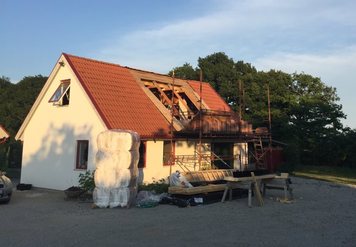 Hus under renovering med delvis avlägsnad byggnadsställning och byggmaterial runtomkring.