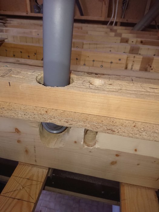 Avloppsrör genomför genom golvbjälklag, redo för väggmontage i pågående badrumsrenovering.