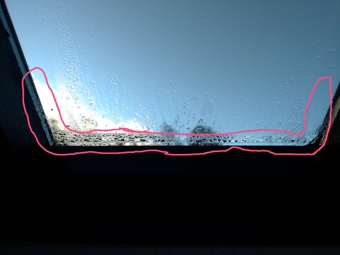 Kondens och fuktskador längs kanten av en ny glaskassett i ett fönster.
