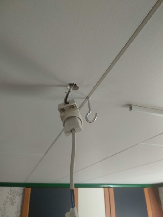 Elektrisk installation med en vit kabel ansluten till en ojordad takdosa, med en krok för armatur och synliga ledningar.