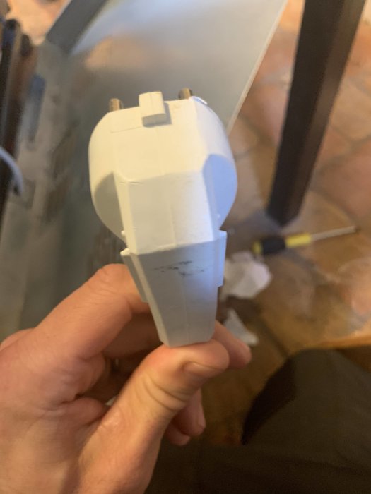 Hand håller en vit elektrisk plugg utan synlig skruv, möjliga användarspår syns.