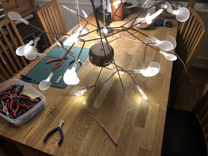 Taklampa med tända glödlampor på matbord med verktyg och verktygslåda.