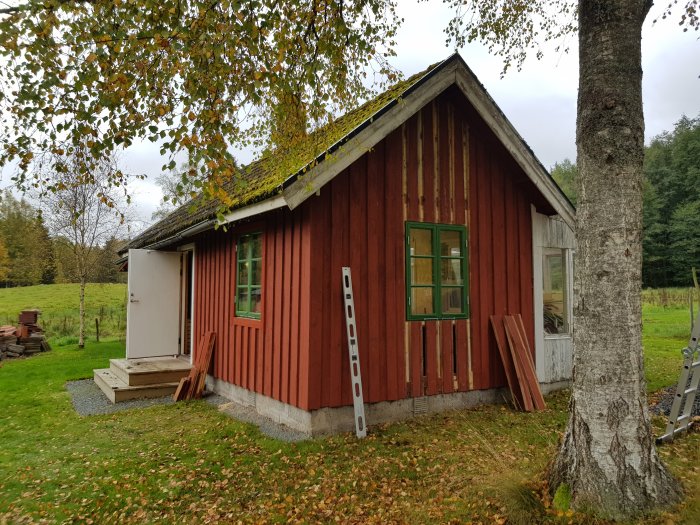 Nyinstallerat fönster i gaveln på en röd gäststuga med färdig panel och ny struken falufärg.