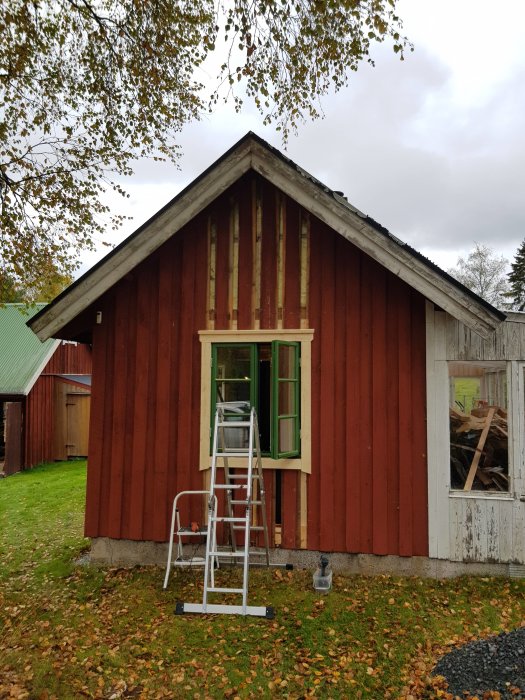 Nyinstallerat fönster med grönt fönsterbleck på röd gäststugas gavel med stege framför.