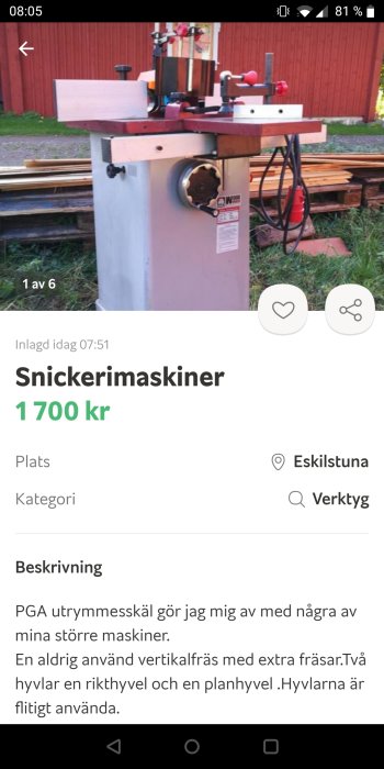 Vertikalfräs verktygsmaskin utställd utomhus med röd byggnad i bakgrunden.