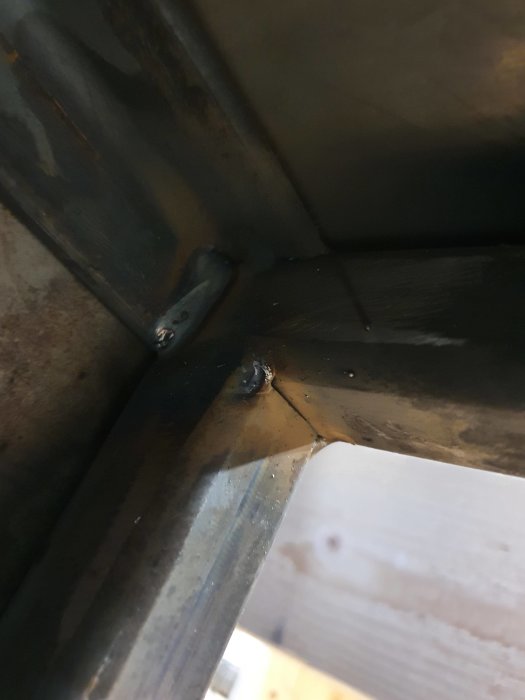 Svetsad metallkonstruktion med synliga fogar och svetspunkter vid en hörnsöm, ej svetsad i kälen.