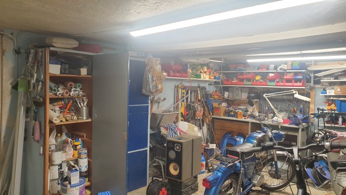 Välorganiserat garage med verktyg, motorcyklar och hyllor fulla av förvaringslådor.