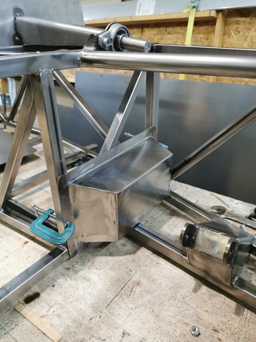 En hembyggd metalld låda fastsatt på en axel bredvid ett rattrör och snap-off fäste, i en verkstad.