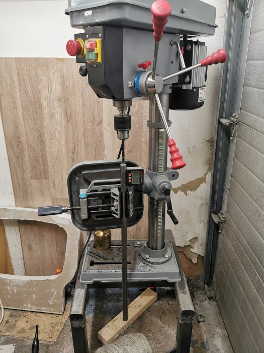 Borrpress med påbyggd låda och snap-off fäste, omgiven av verktyg och byggmaterial.