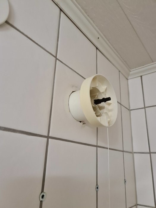 Tilluftsventil i vägg med kakelplattor som användaren överväger att byta till frånluftsfläkt.
