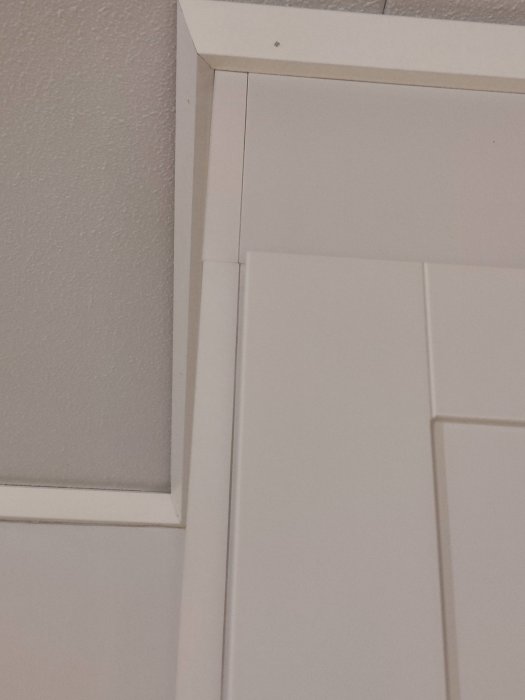 Detalj av en vit täcksida på en möbel som inte når upp till taket, skapar en synlig glipa.