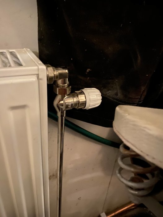 Termostat med vit ratt kopplad till ett element i ett garage med fråga om justering av värme.