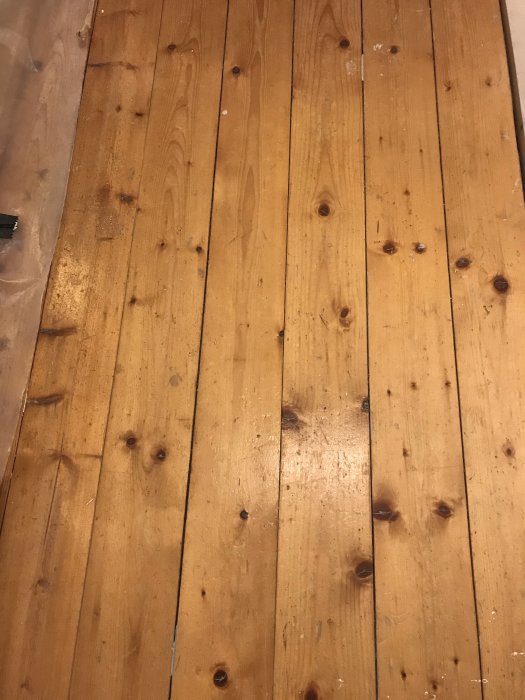 Ljust trägolv med furuplank, söker matchande plank för renovering, 100x25 mm storlek behövs.