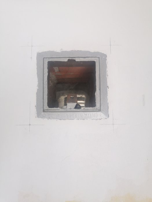 Tilluftsdon i vägg under installation, utan front, synliga tegelstenar och rör inuti.