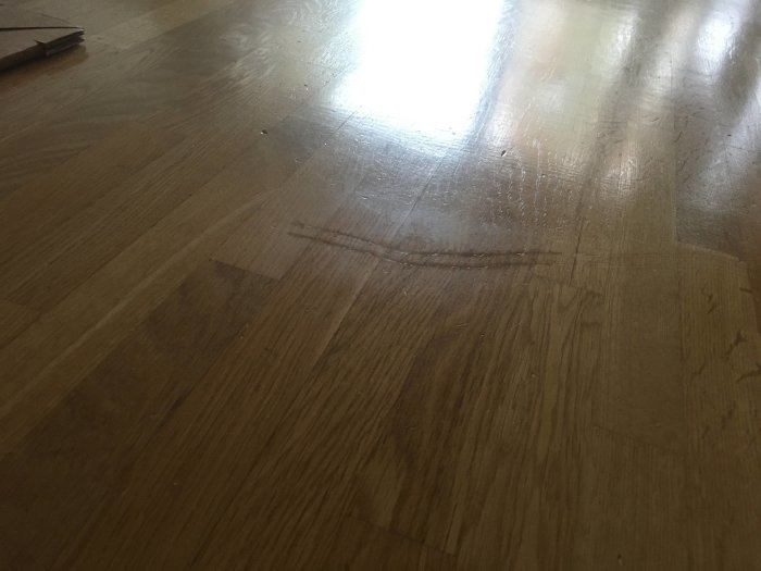 Repad yta på ett trägolv med synlig glansskillnad efter försök till reparation med vax.