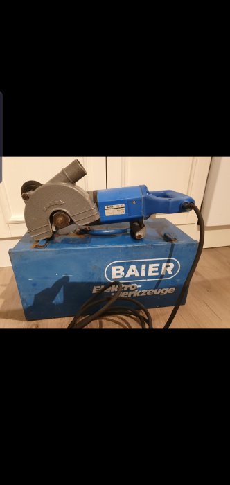 Begagnad betongkap/betongspårmaskin från Baier, blå och grå, utan klingor, modell BDN 453, ligger på en trälåda.