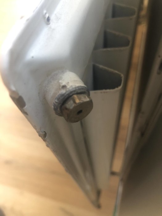 Närbild på en potentiell luftventil på ett vitt element som ser slitet ut.