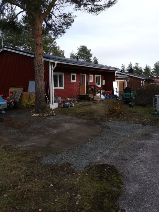 Grusad yta framför hus med 0-18 stenmaterial där fiberkabel lagts, omgiven av träd och buskar.