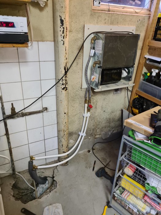 Installationsprocess för värmesystem i garage med synliga rör och elektriska komponenter.