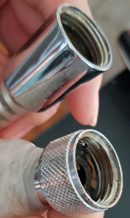 Närbild på två ändar av en flexibel badrumsslang som hålls upp bredvid varandra.