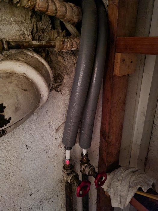 Nyanslutna vattenledningar utan läckage, med isolering och röda ventiler mot en vägg.