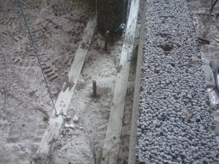 Nyguvet betonggolv med armeringsjärn, skrovlig yta och förberedelse för murning av innervägg.