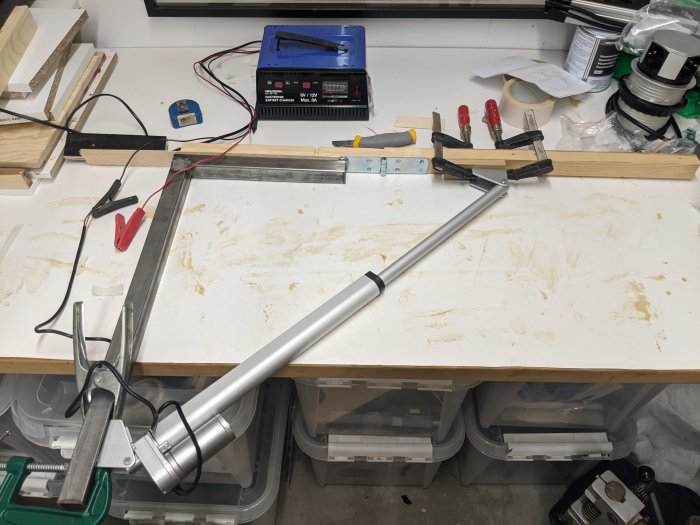 Verkstadsbord med svetsutrustning, metallvinkel i tving och materialrester.