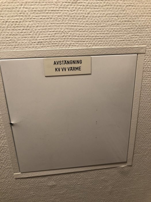 Stängningslucka för värme med texten "AVSTÄNGNING KV VV VÄRME" på vit etikett.