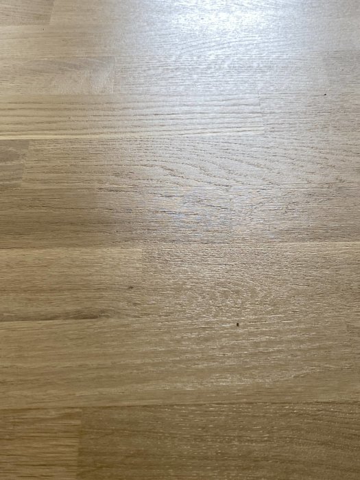 Nyligen slipat och lackat trägolv med synliga ojämnheter och mindre defekter vid närbild.