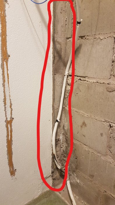 Vertikal yta med kablar för putsning, markerad med rött, intill betongvägg.