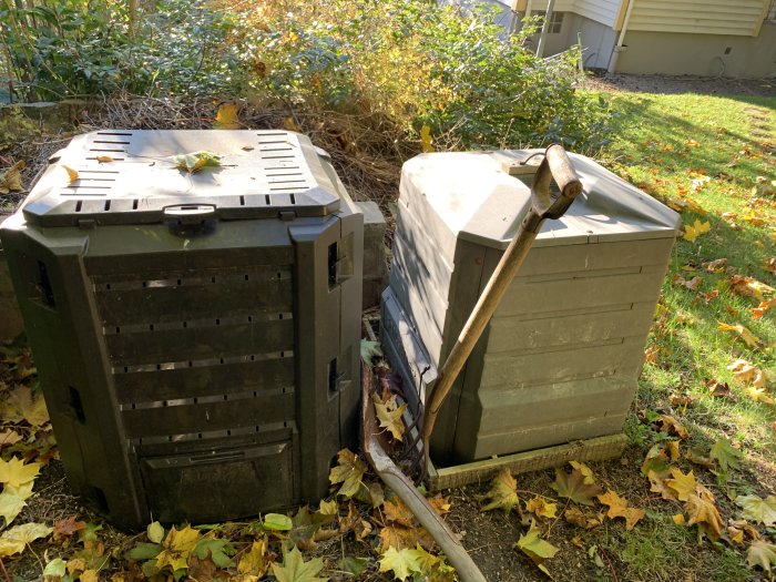 Kallkompost till vänster och varmkompost till höger i en trädgård omgiven av höstlöv och en spade lutad mot den högra.