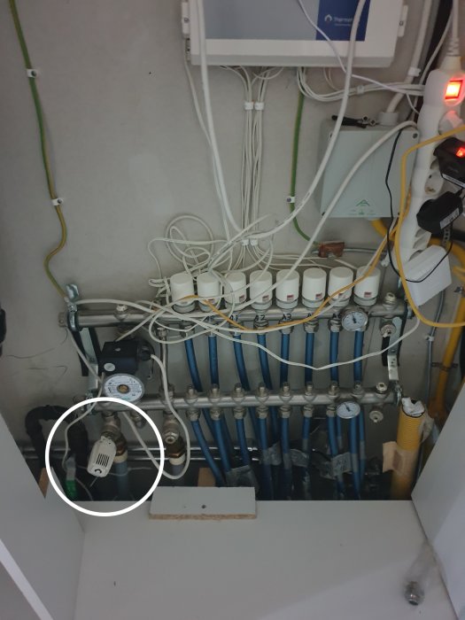 Värmesystem med rör, termostater och blandventil i ett hus med golvvärme.