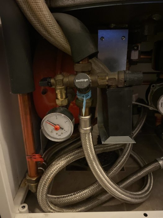 Inre del av värmepump med sladdar, rör, ventiler och tryckmätare.