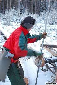 Person använder en Hällnäslyft för att lyfta en stock i vinterlandskap.