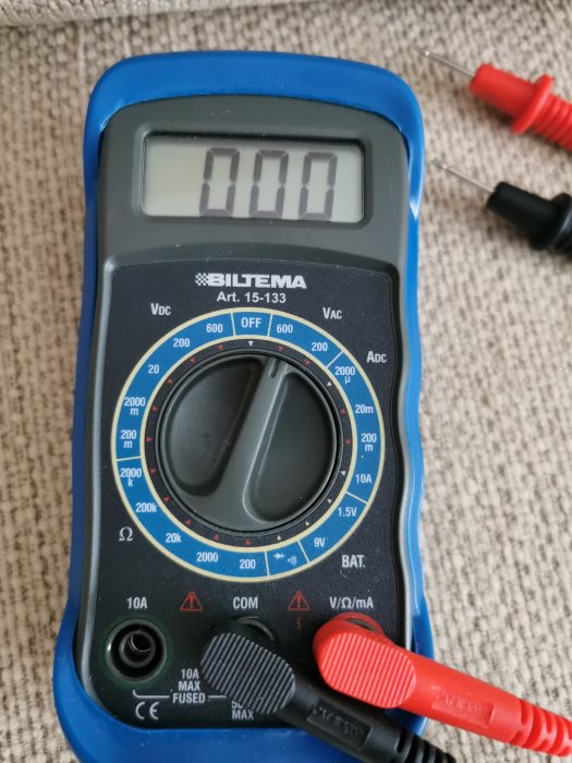 Multimeter inställd på spänningsmätning med visad display och testledningar.