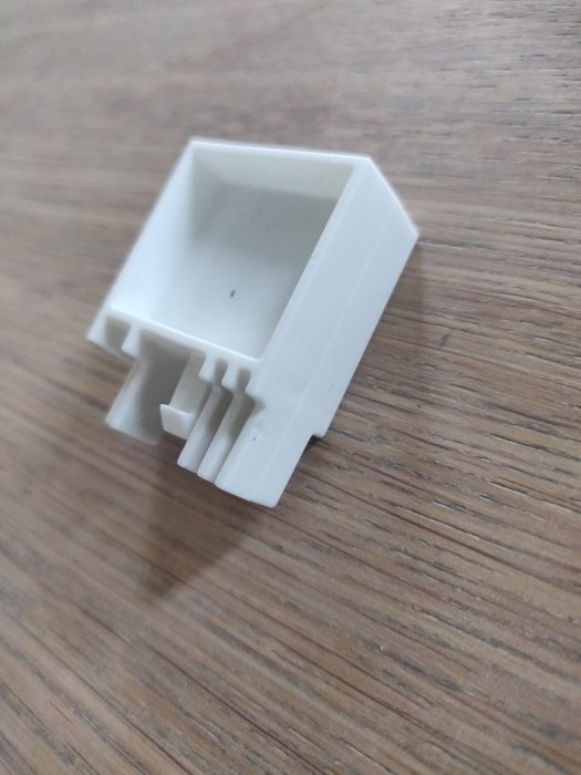 Vit plastplugg som liknar en sockerbit, troligen en reservdel från en Electrolux frys.