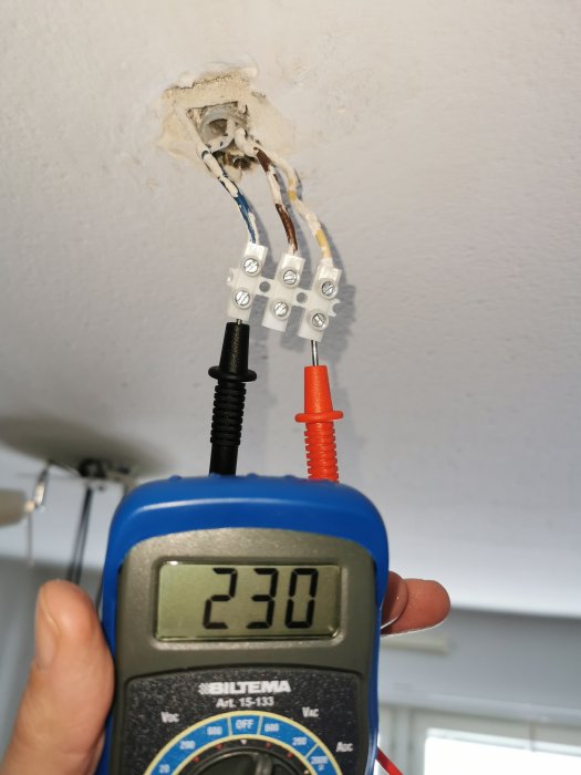 Multimeter visar 230V vid eluttagstillkoppling där en brun ledning synes inaktiv.