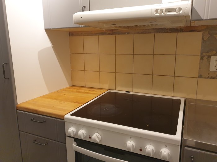 Kök med ofullständig kakelvägg där en list har tagits bort, exponerande vägg och limrester.
