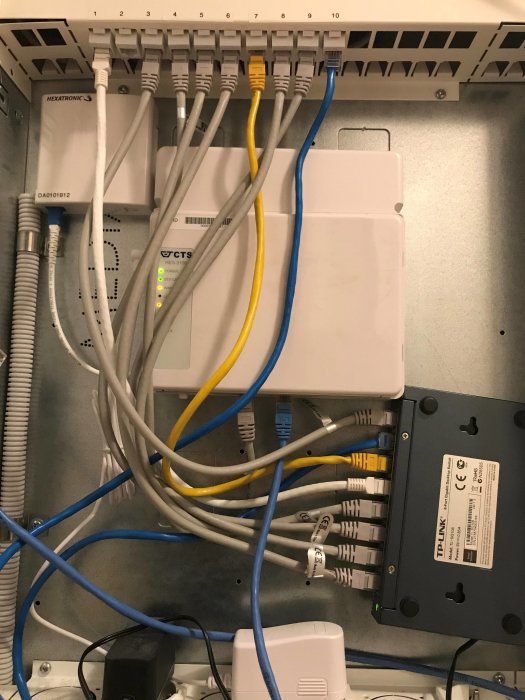 Nätverksskåp med patchpanel, tjänstefördelare, router och switch anslutna med flera Ethernetkablar.