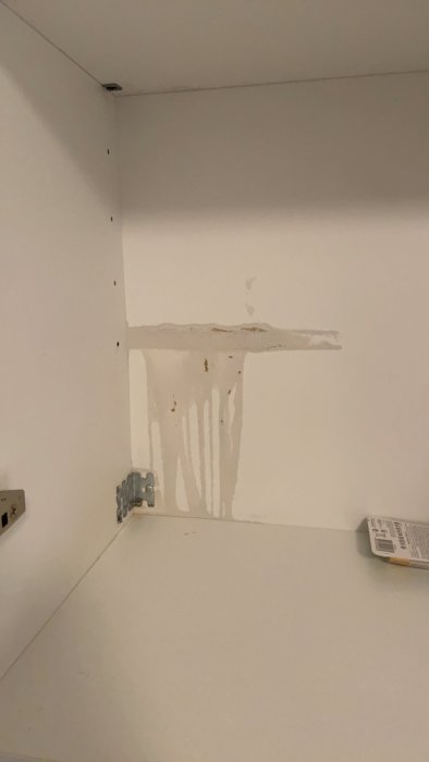 Missfärgat och svullet område på spånskiva i badrumsskåp efter tvålläckage.