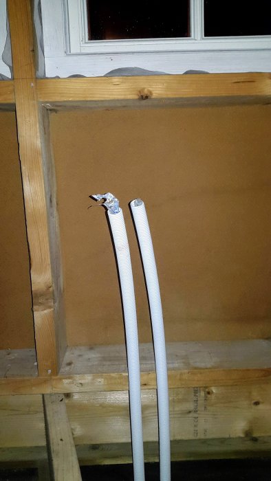 Pex rör-i-rör som sticker upp från ett bjälklag bredvid ett fönster i ett rum under renovering.