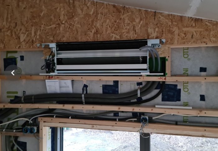 Installation av frikyla med rör och elektriska kopplingar i en öppen väggkonstruktion.